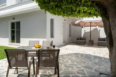 a patio with a table and chairs and an umbrella at Duo Verde Soil Garden Apartment in Kremasti