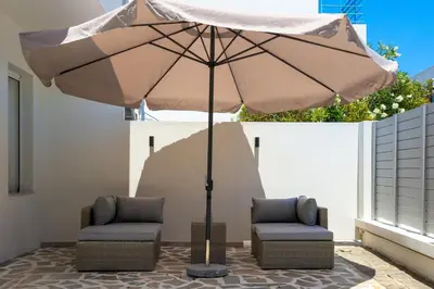 two chairs under an umbrella on a patio at Duo Verde Soil Garden Apartment in Kremasti