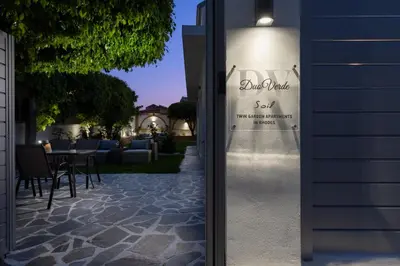 a sign for a hotel with a table and chairs at Duo Verde Soil Garden Apartment in Kremasti