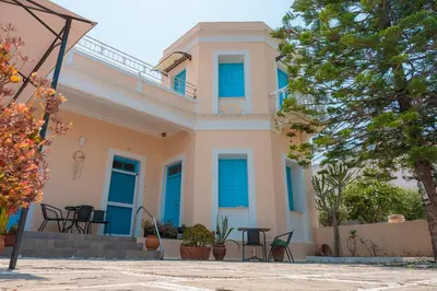 a house with blue windows and tables in front of it at 1944-Heritage House in Lardos