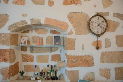 a clock hanging on a stone wall with a shelf at 1944-Heritage House in Lardos