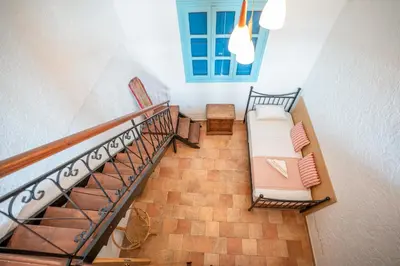 a room with a staircase with a couch and a window at 1944-Heritage House in Lardos