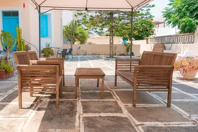 three wooden chairs and a table under an umbrella at 1944-Heritage House in Lardos