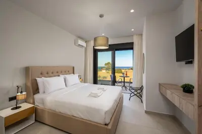 a bedroom with a large white bed and a balcony at Terra Magna Villas in Kiotari
