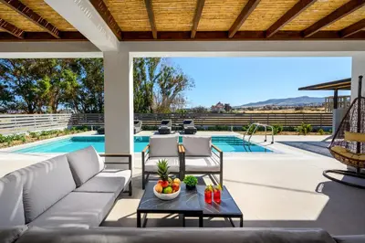 an outdoor patio with a couch and chairs and a pool at Terra Magna Villas in Kiotari
