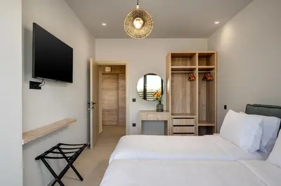 a bedroom with two white beds and a flat screen tv at Terra Magna Villas in Kiotari