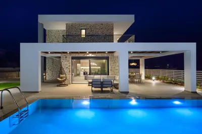 a villa with a swimming pool at night at Terra Magna Villas in Kiotari