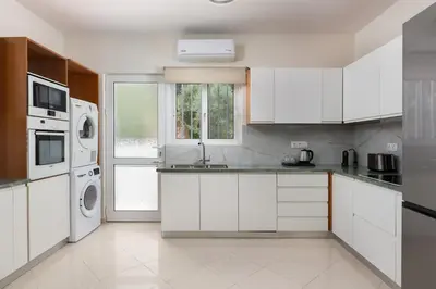 a kitchen with white cabinets and a washer and dryer at Celestial City Suite in Rhodes Town
