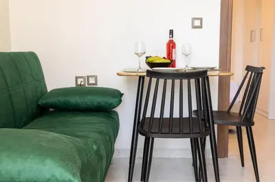 a living room with a green couch and a table and chairs at Nikargy Avra in Koskinou
