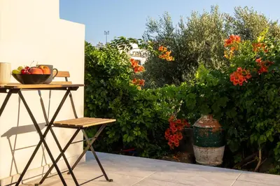 a table and chair next to a garden with flowers at Nikargy Avra in Koskinou
