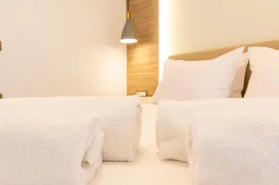 a bedroom with two beds with white sheets and pillows at Nikargy Avra in Koskinou