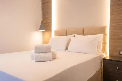 a bedroom with a white bed with a chair at Nikargy Avra in Koskinou