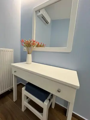 a white dressing table with a mirror and a vase with flowers at Charavgi House in Archangelos
