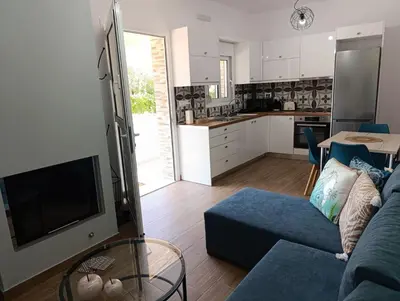 a living room with a blue couch and a kitchen at Charavgi House in Archangelos