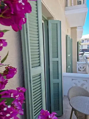 a pair of green shutters on a building with purple flowers at Rhodes Port Stories in Rhodes Town