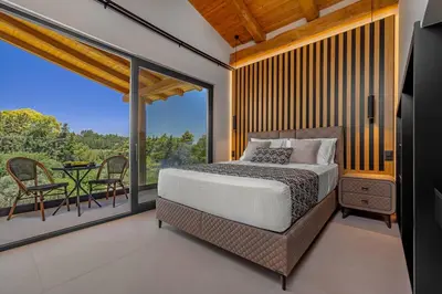 a bedroom with a bed and a balcony with a table at Costas Luxury Villas - Costa's Villa in Koskinou