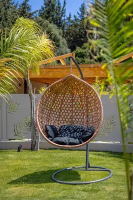 a wicker chair sitting on the grass in a yard at Costas Luxury Villas - Costa's Villa in Koskinou