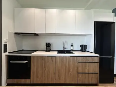 a kitchen with white cabinets and a black refrigerator at Aelios Petra sea view apartment 4 in Asgourou
