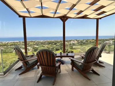 a patio with chairs and a table and a view of the ocean at Aelios Petra sea view apartment 4 in Asgourou