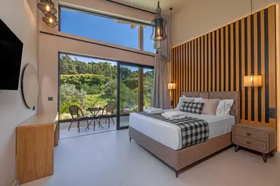 a bedroom with a large bed and a balcony at Costas Luxury Villas - Athena's Villa in Koskinou