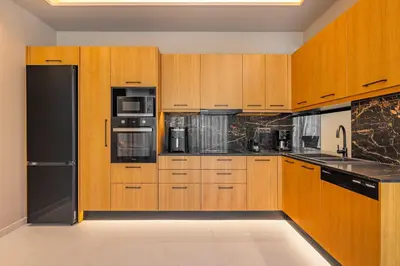 a kitchen with wooden cabinets and a black refrigerator at Costas Luxury Villas - Athena's Villa in Koskinou