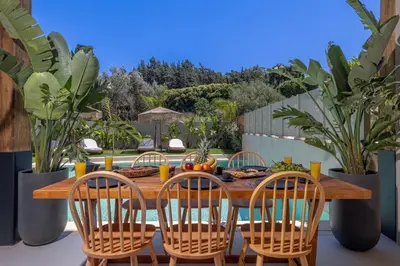 a wooden table with chairs and a table with food on it at Costas Luxury Villas - Athena's Villa in Koskinou