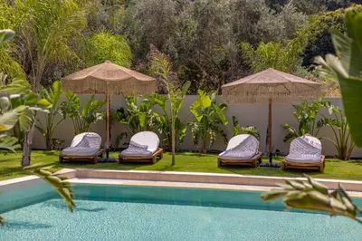 a group of chairs and umbrellas next to a pool at Costas Luxury Villas - Athena's Villa in Koskinou