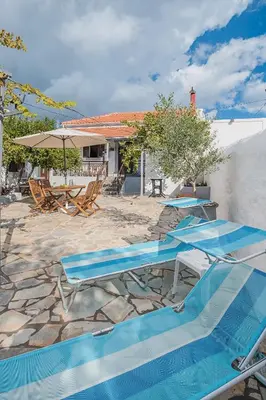a patio with two blue chairs and a swimming pool at Casa La Perla - Lachania in Lachania