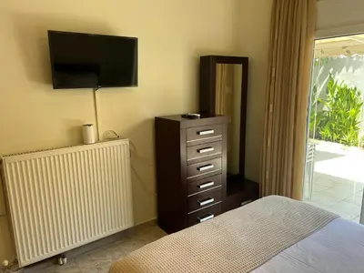 a bedroom with a bed and a dresser with a television at Cozy Kolonaki Retreat in Kremasti