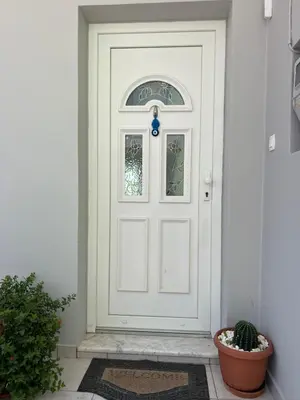 a white door with a window and a potted plant at Cozy Kolonaki Retreat in Kremasti