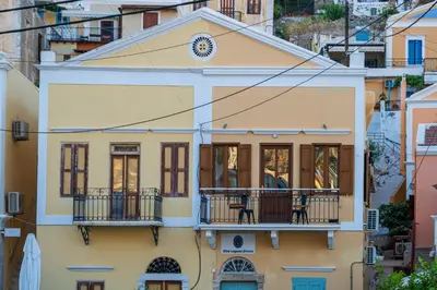 a yellow house with balconies on a city street at La Casa di Symi - Central Apartment with View in Symi