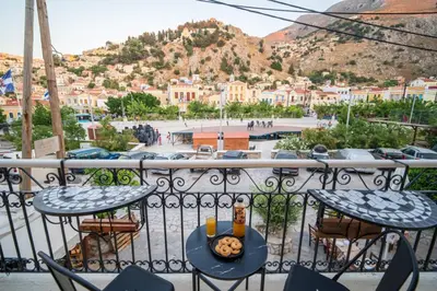 a table and chairs on a balcony with a view of a city at La Casa di Symi - Central Apartment with View in Symi