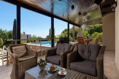 a patio with wicker chairs and a table and a pool at Calypso Lindia Luxury Villa in Líndos
