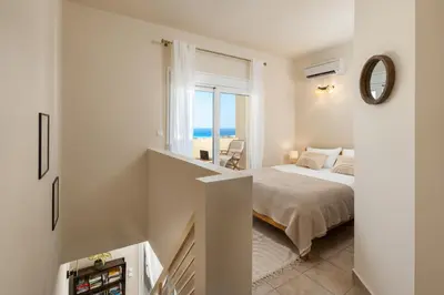 a bedroom with a bed and a view of the ocean at Calypso Lindia Luxury Villa in Líndos