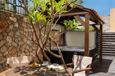a patio with a table and chairs and a tub at Calypso Lindia Luxury Villa in Líndos