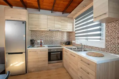 a kitchen with wooden cabinets and a stainless steel refrigerator at Garden Olive Luxury Villa in Archangelos