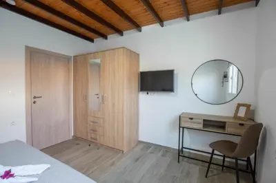 a bedroom with a bed and a desk and a mirror at Garden Olive Luxury Villa in Archangelos