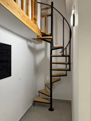 a black spiral staircase in a white room at Radiki in Gennadi