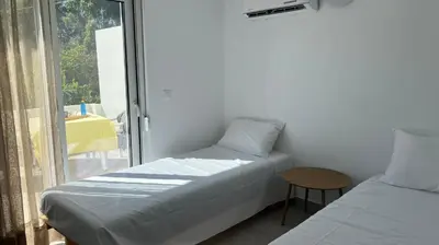 a bedroom with two beds and a table and a window at Radiki in Gennadi