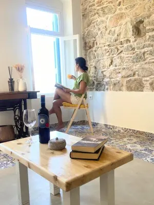a woman sitting in a chair looking out the window at ALEMINAS House 2 in Symi