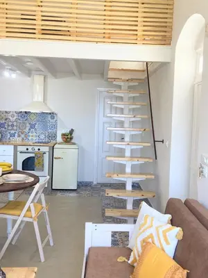 a spiral staircase in a living room next to a kitchen at ALEMINAS House 2 in Symi