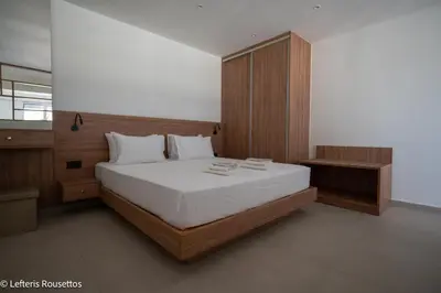 a bedroom with a large bed and a wooden cabinet at Rodos Suites on the Park in Rhodes Town