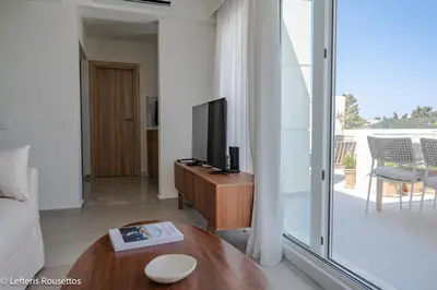 a living room with a television on a wooden table at Rodos Suites on the Park in Rhodes Town