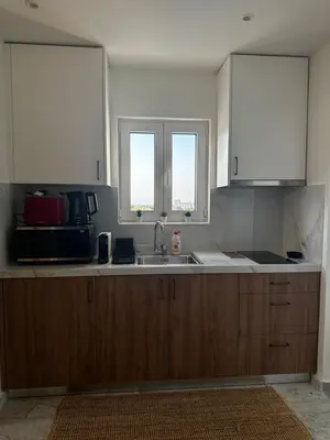 a kitchen with wooden cabinets and a sink and two windows at Rodos Suites on the Park in Rhodes Town