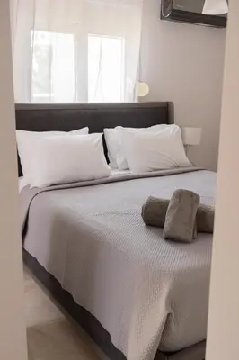 a bedroom with a bed with white sheets and pillows at Seabreeze By Ro in Rhodes Town