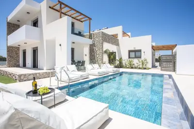 a villa with a swimming pool in front of a house at Nostos Luxury Apartments in Kremasti