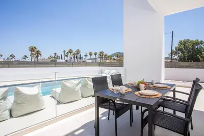 a dining room with a table and chairs on a balcony at Nostos Luxury Apartments in Kremasti