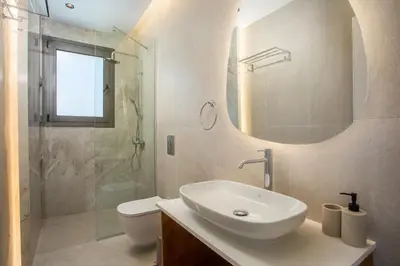 a white bathroom with a sink and a shower at Nostos Luxury Apartments in Kremasti