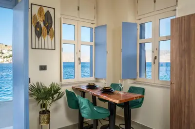 a dining room with a table and chairs and windows at Symi's Jewel in Symi