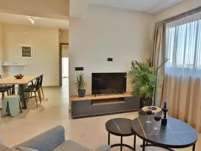 a living room with a television and a table and chairs at Bliss Sunrise Penthouse in Asgourou